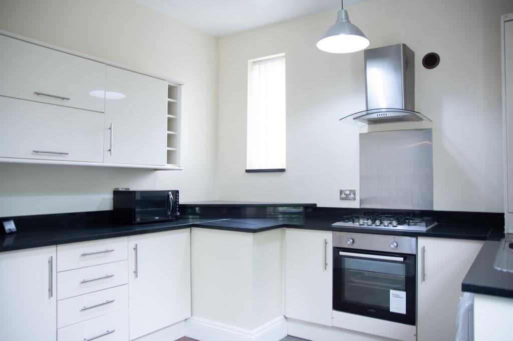 Modern kitchen with sleek white cabinets, black...