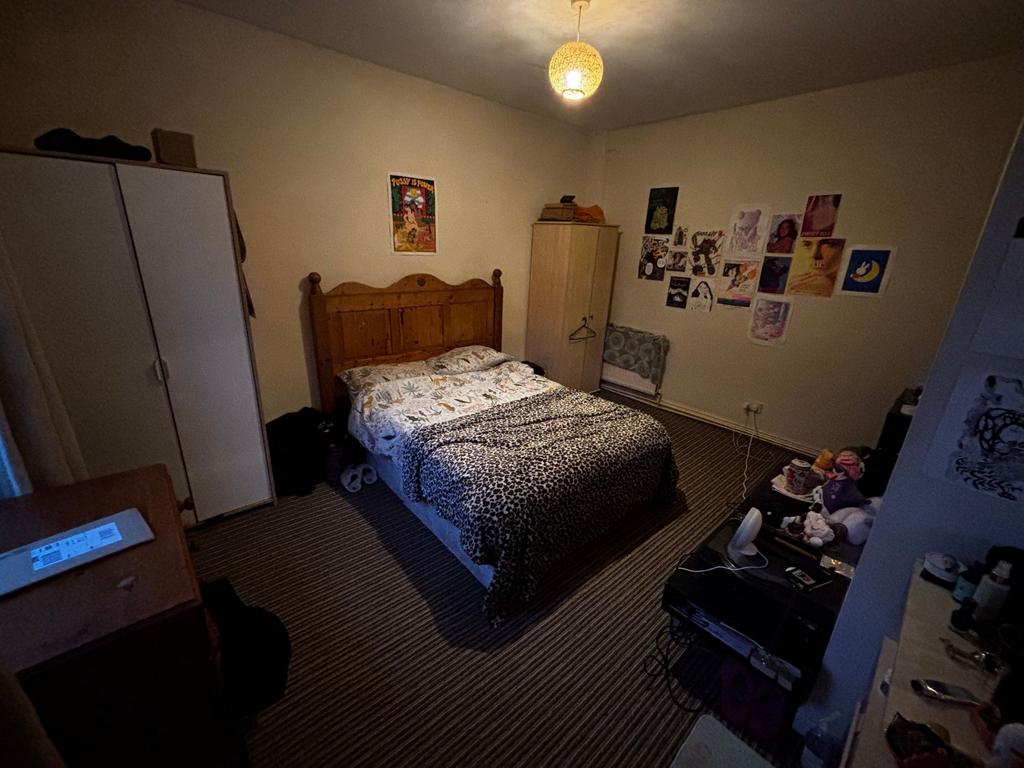 Cosy double bedroom with a wooden headboard, pa...