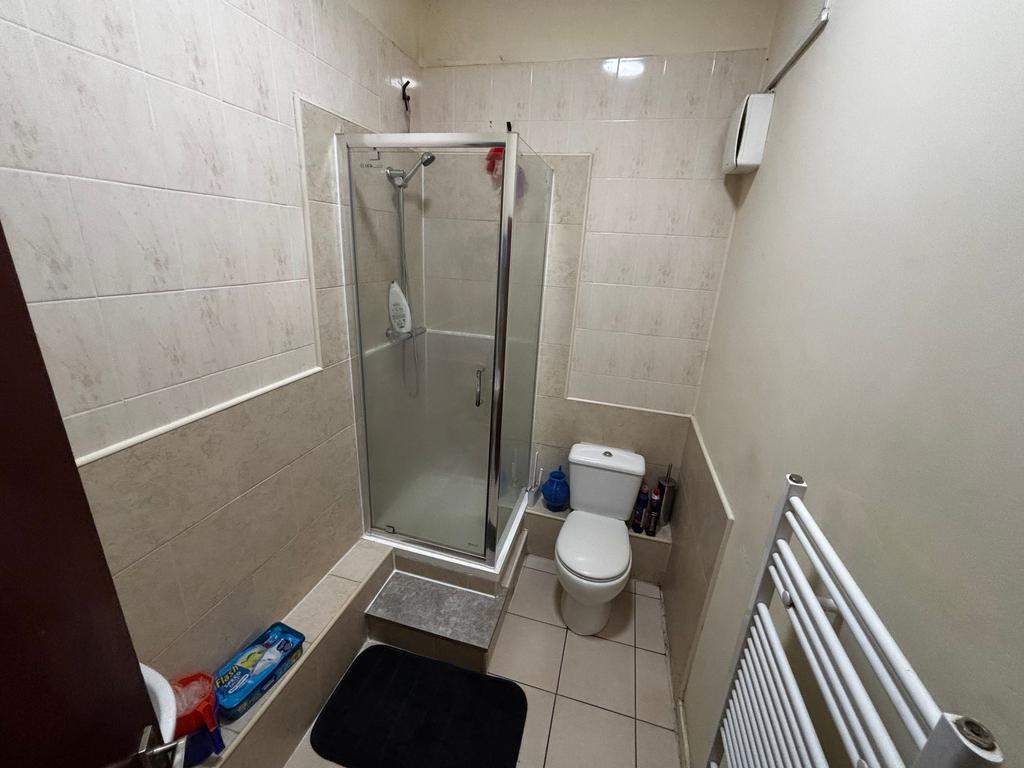 Compact tiled bathroom with a corner shower cub...