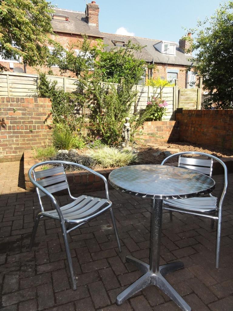 Sunny private paved patio with a metal bistro t...