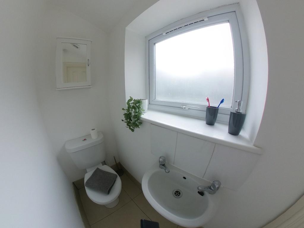 Bright, clean bathroom with white walls, froste...
