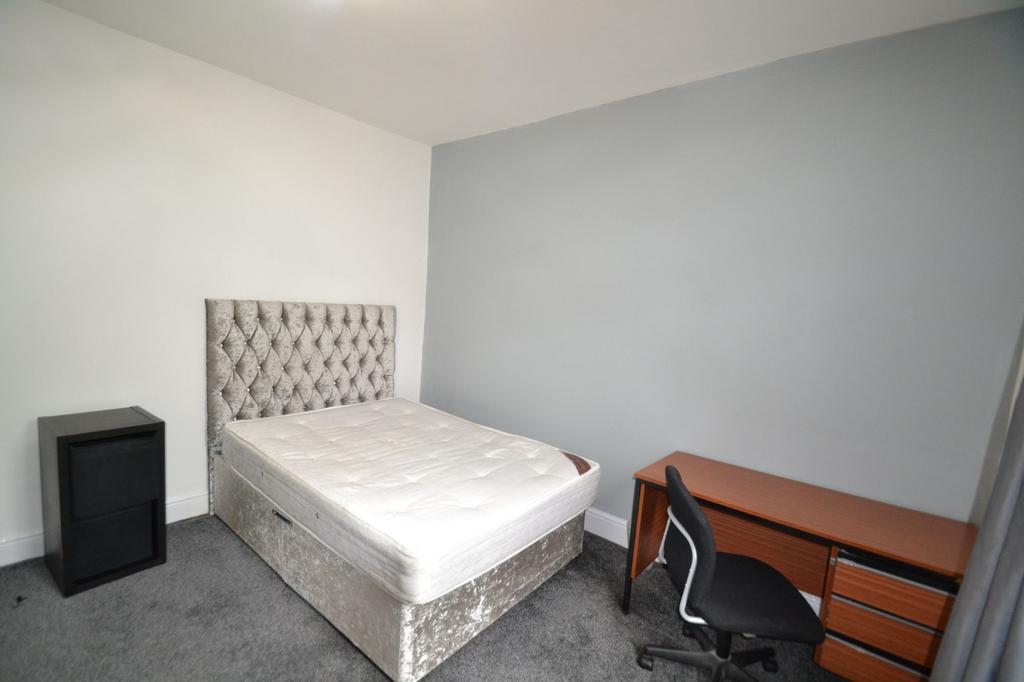 A tidy and minimalist bedroom featuring a comfo...