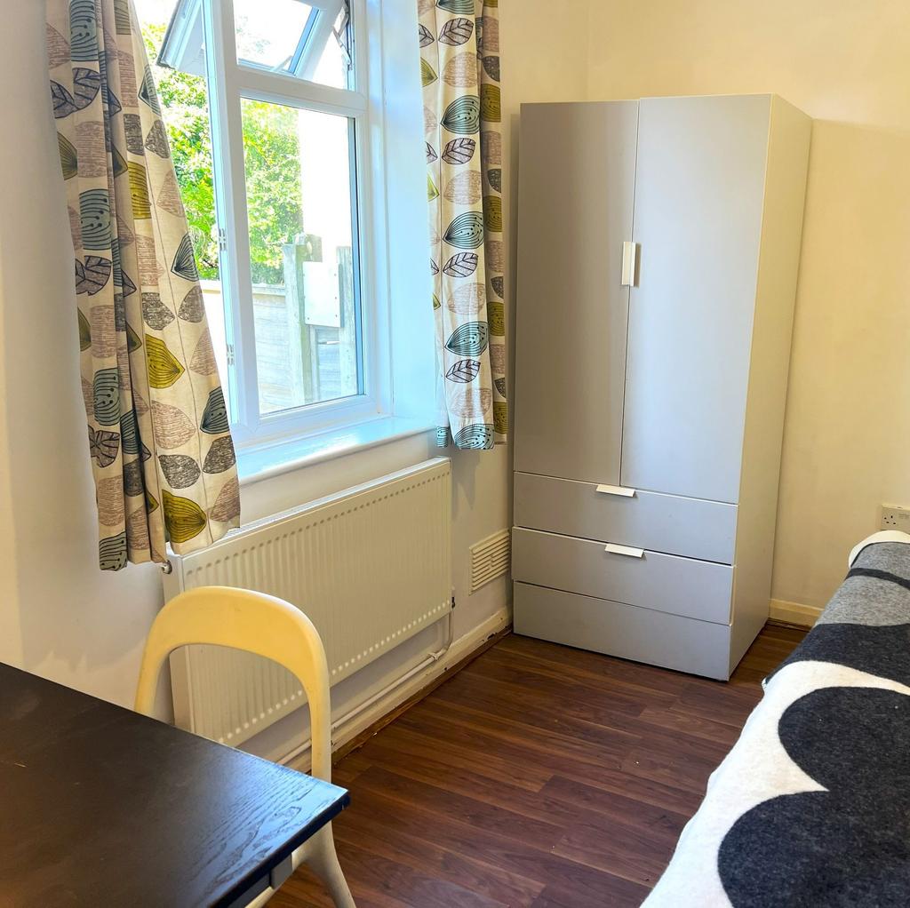Bright single bedroom with large window and pat...