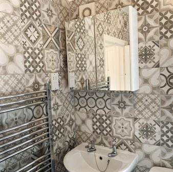 Stylish tiled bathroom with patterned ceramic t...
