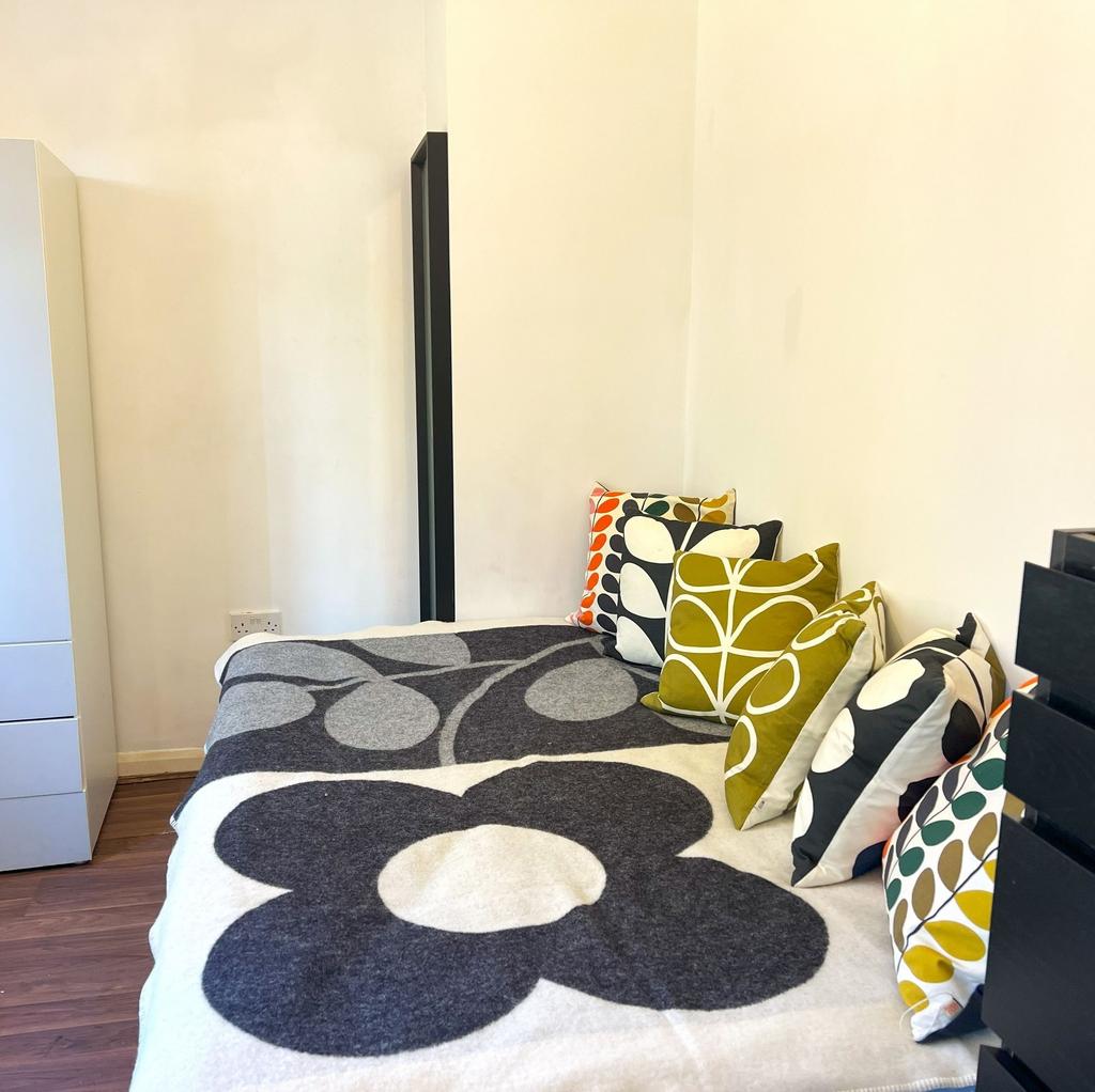 Cozy single bedroom with patterned cushions and...