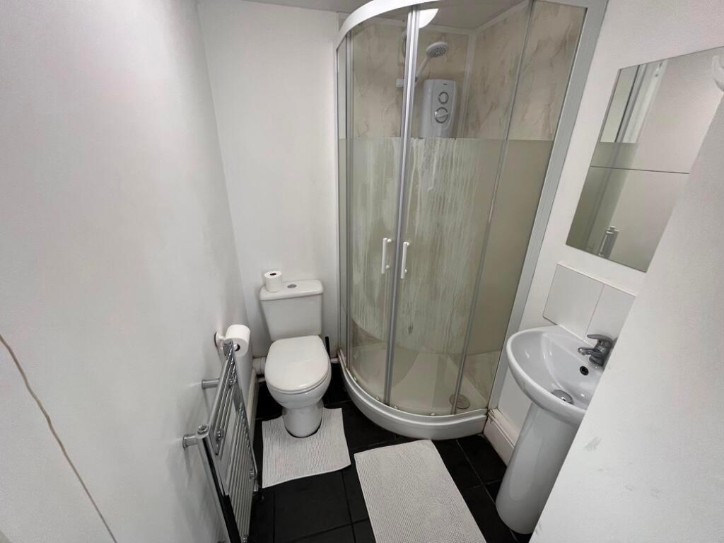 Bright, modern bathroom with a curved glass sho...