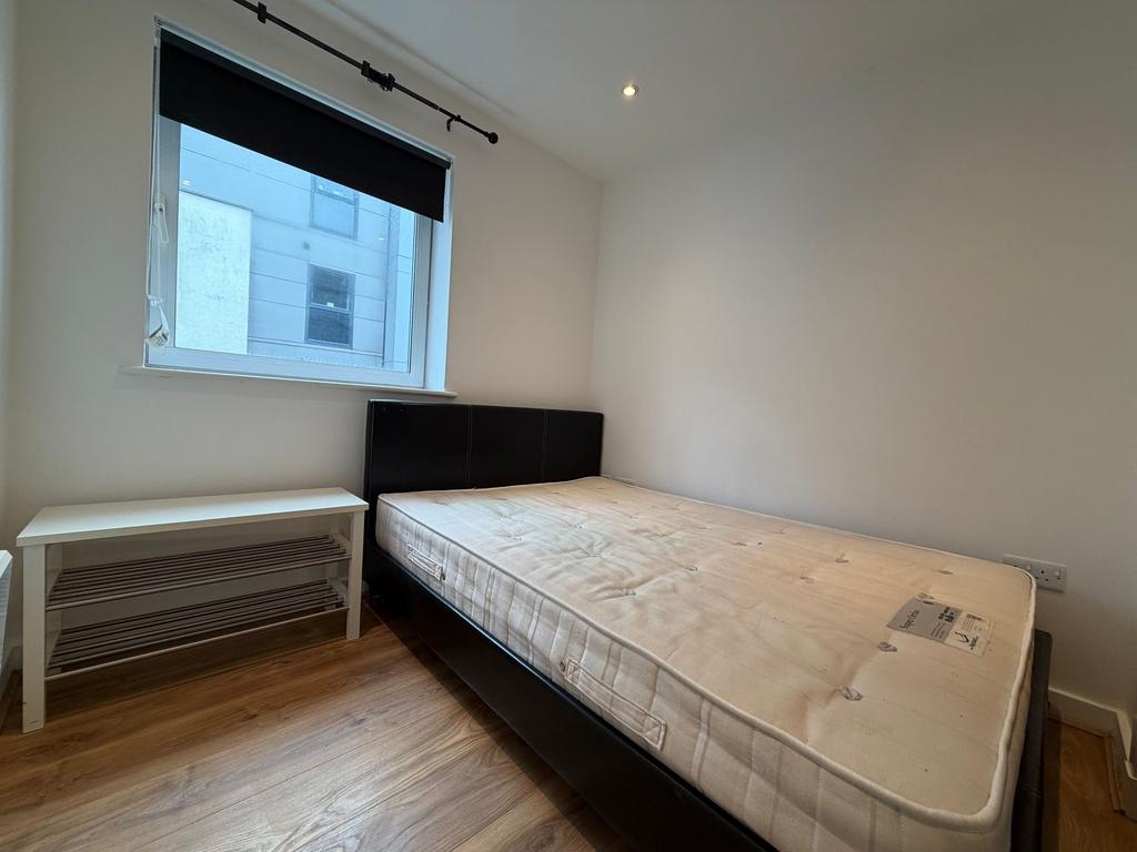 Bright, simply furnished bedroom with a double ...
