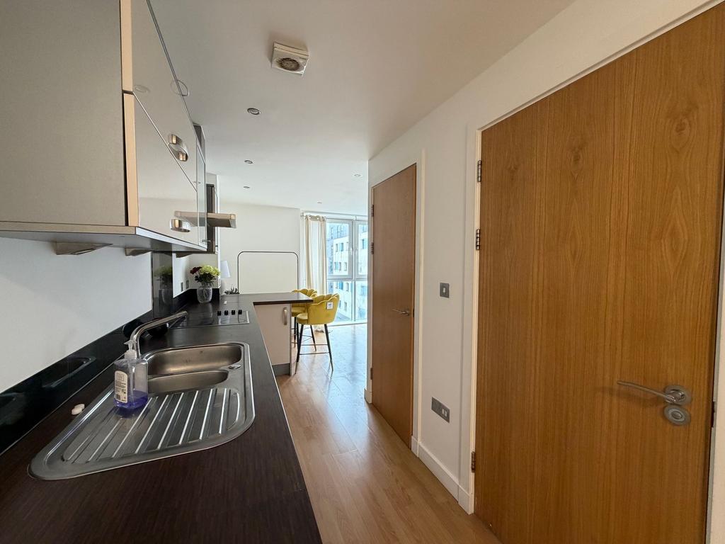 Modern galley-style kitchen with dark worktops,...