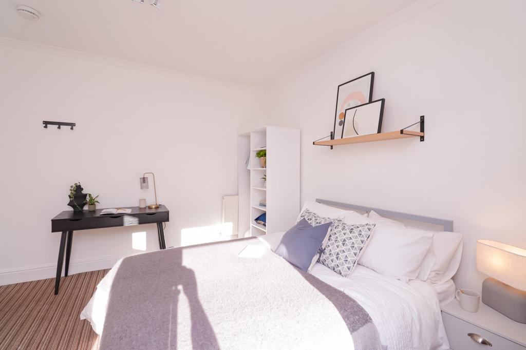 A bright and inviting double bedroom with styli...
