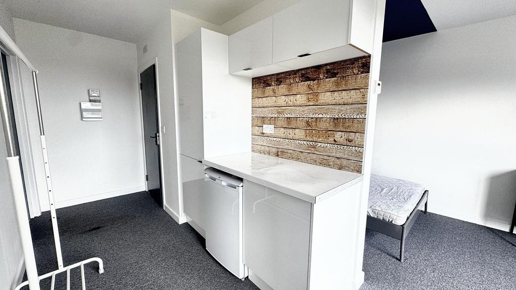 Bright compact kitchenette with white cabinetry...