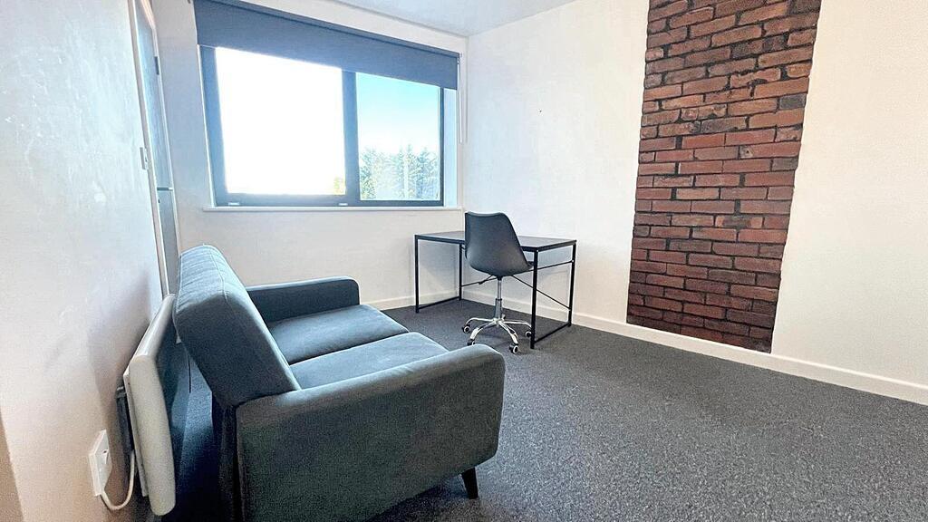 Bright, simply furnished bedroom with a comfort...