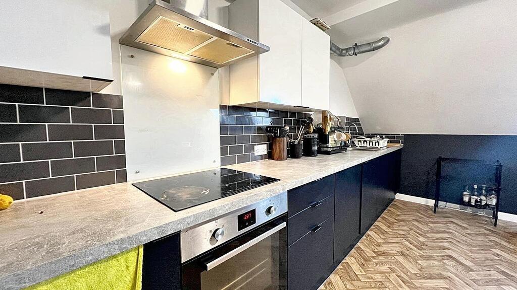 Modern galley-style kitchen with sleek dark low...