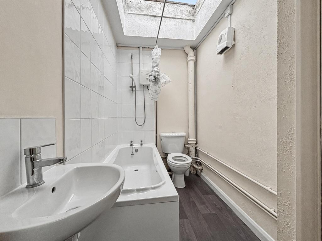 Bright, tidy bathroom with a bathtub, overhead ...