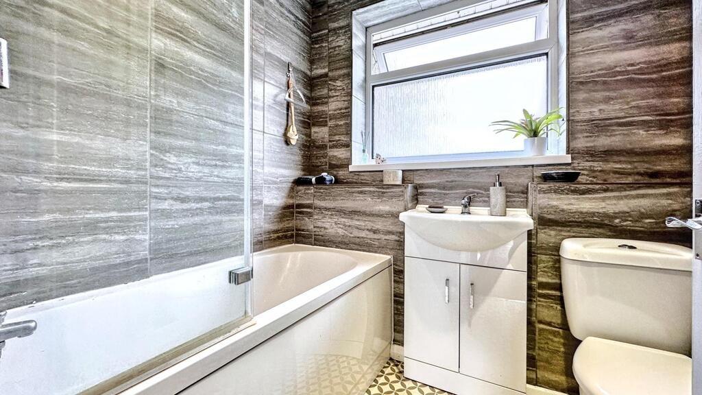 Bright, modern bathroom with a bath and shower ...