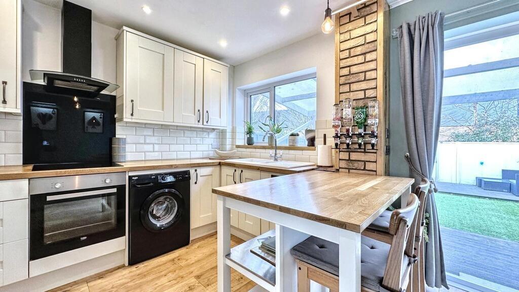 Bright modern kitchen with white cabinetry, woo...