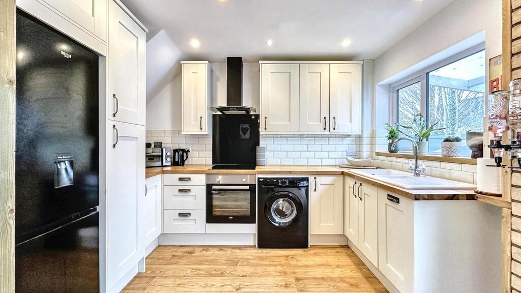 Bright modern kitchen with white cabinetry, int...