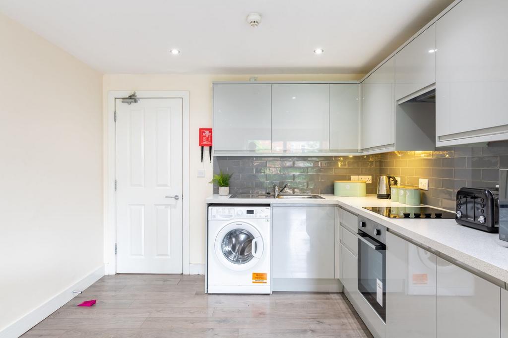 Modern fitted kitchen with glossy pale grey cab...