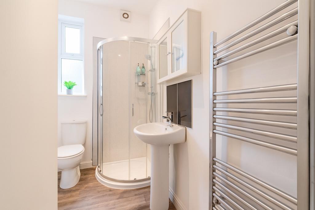 Bright, modern bathroom with a curved glass sho...