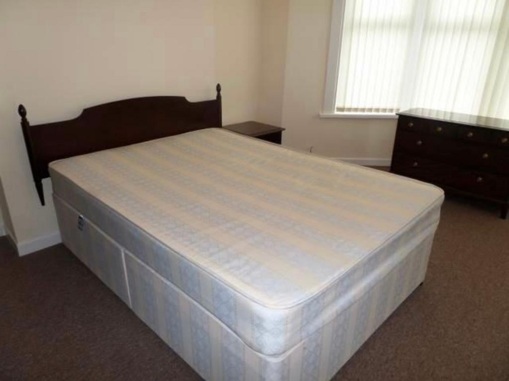 Bright, simply furnished bedroom with a double ...