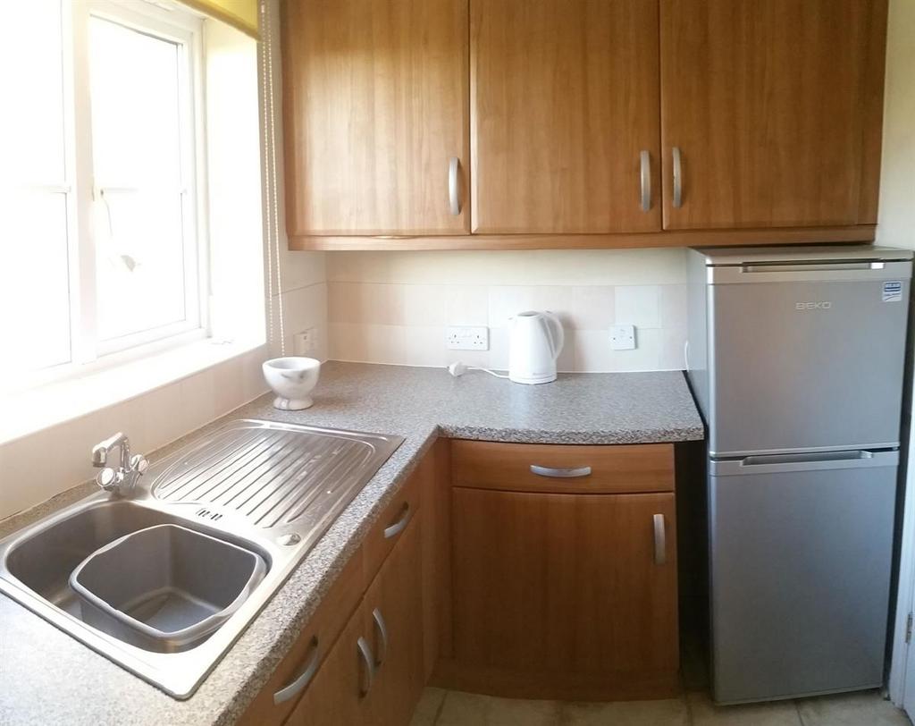 Well-lit compact kitchen with a large window, s...