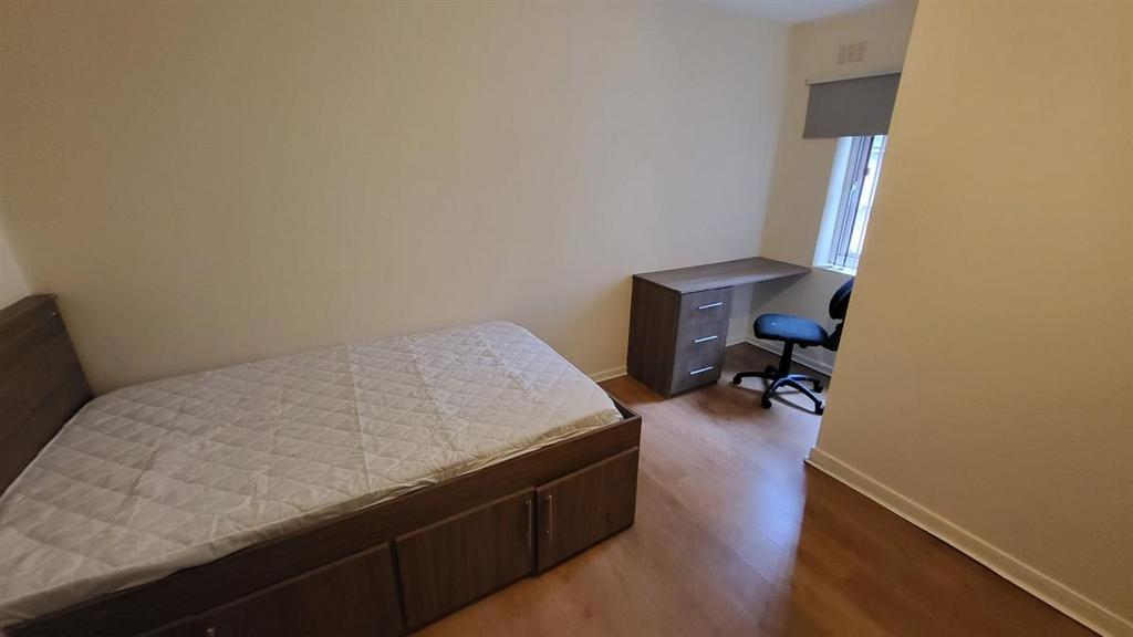 Neat, simply furnished bedroom with a bed, desk...