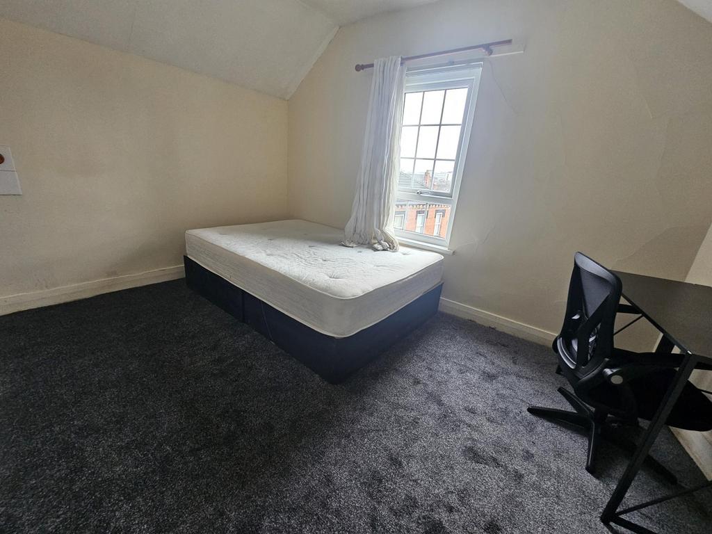 Bright, simply furnished bedroom with a double ...