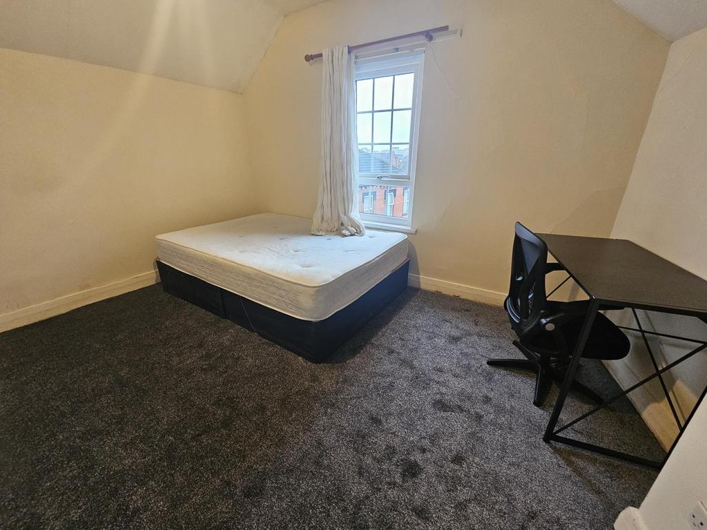 Bright, simply furnished bedroom with a double ...