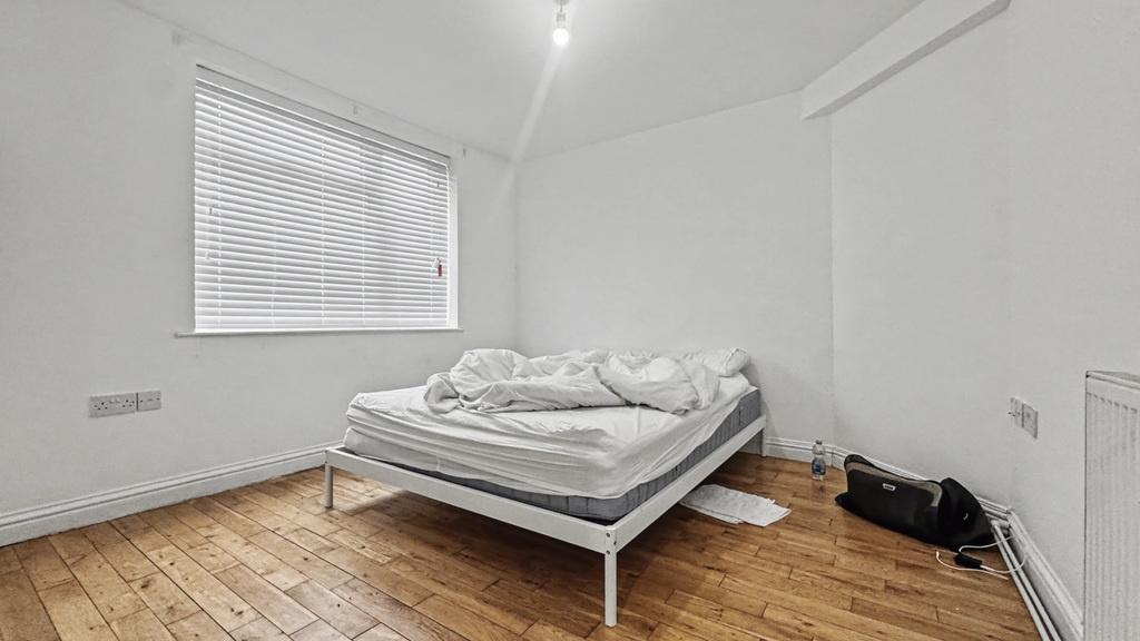 Bright, simply furnished bedroom with wooden fl...