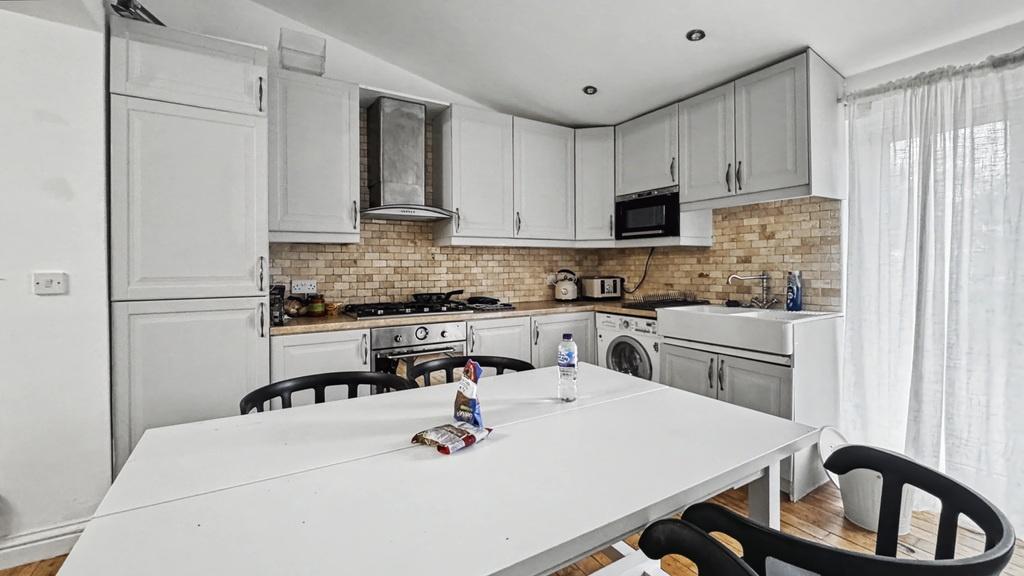 Bright, modern kitchen with white cabinetry, a ...