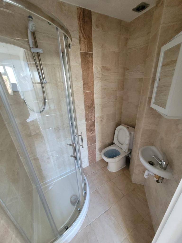 Neatly tiled bathroom with a curved glass showe...