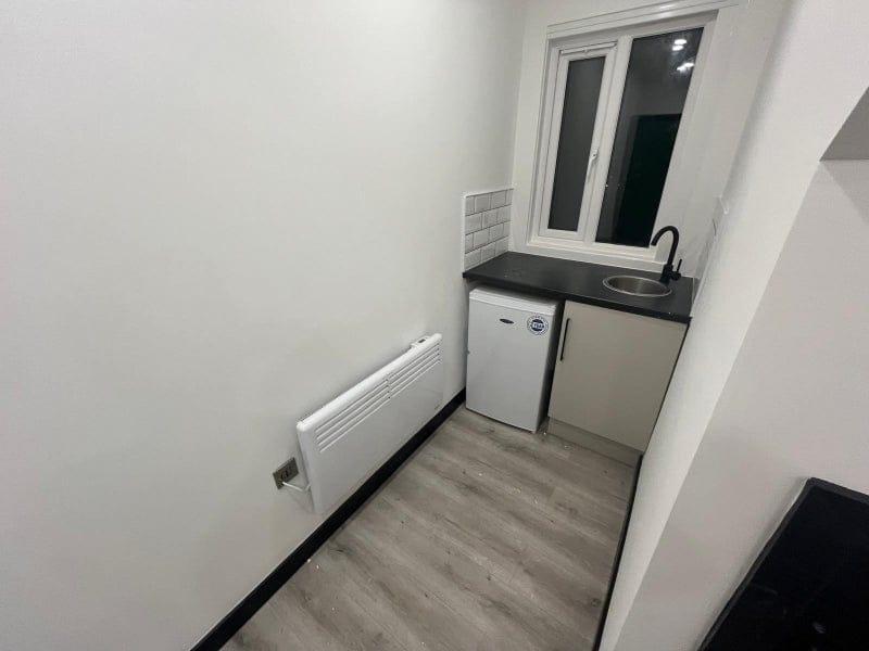 Compact kitchenette with a countertop sink, und...