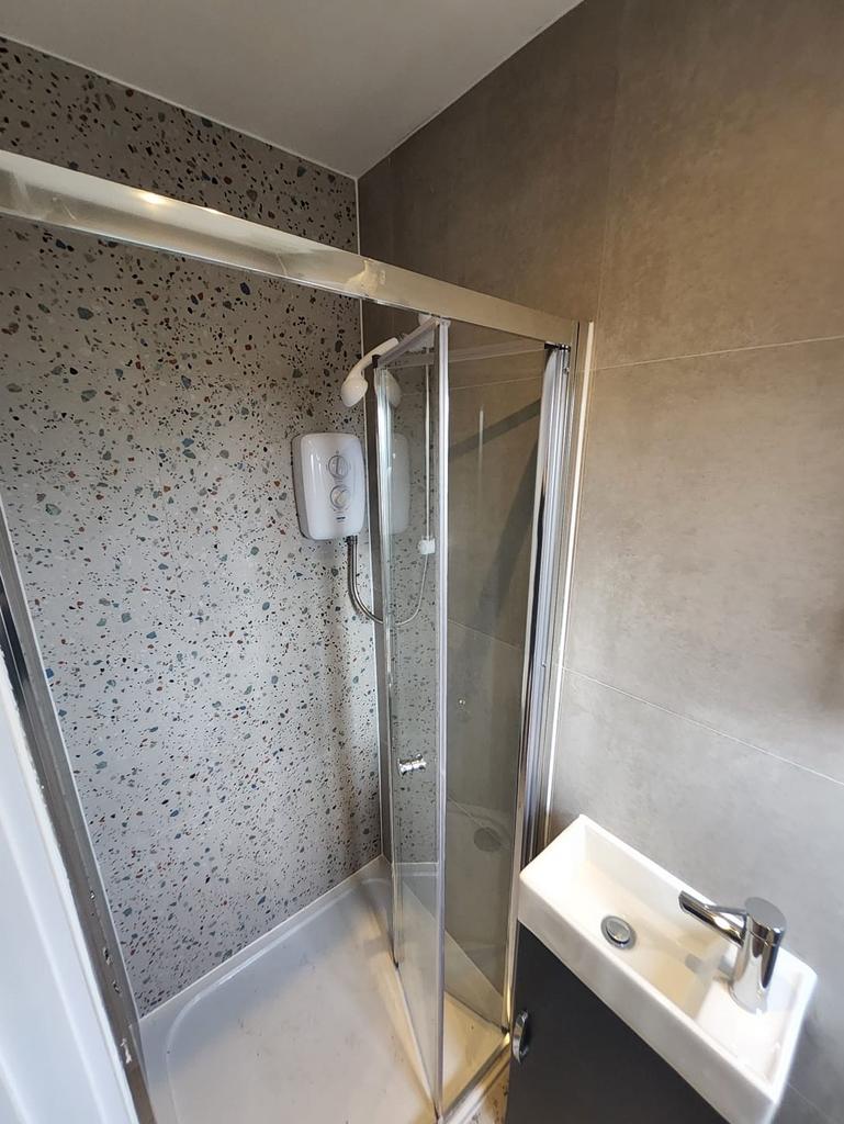 Compact modern bathroom with a corner shower cu...