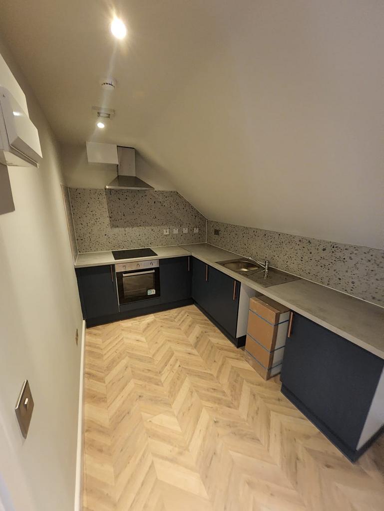 Modern fitted kitchenette with sleek dark cabin...