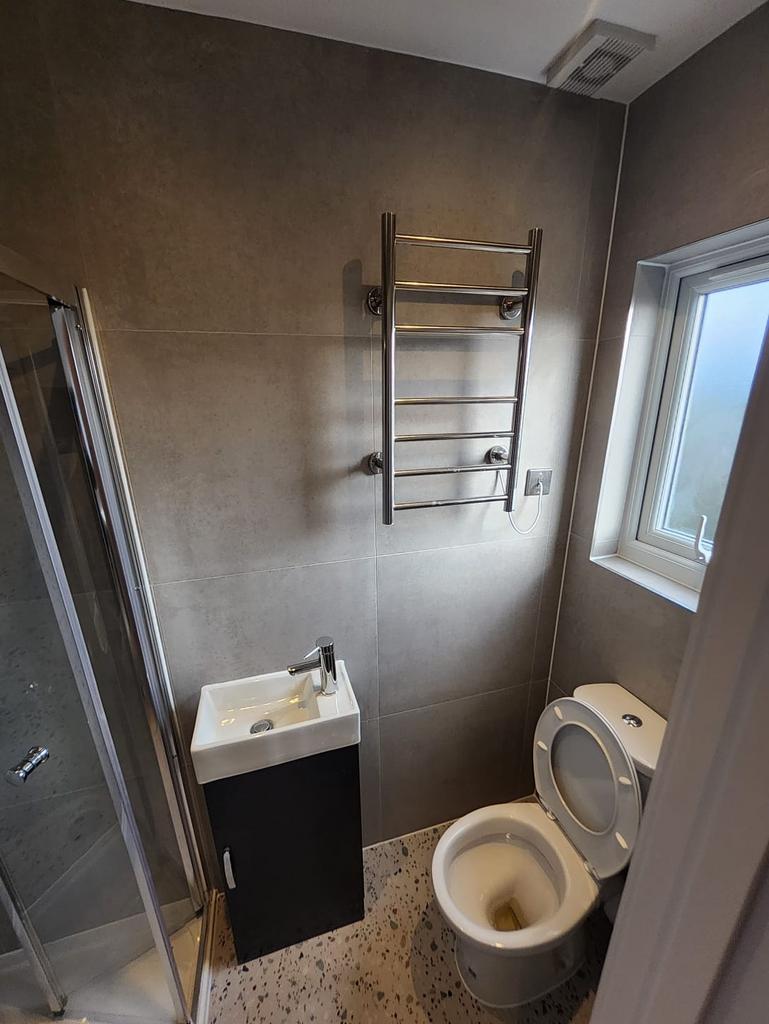 Compact modern bathroom with a corner shower, w...