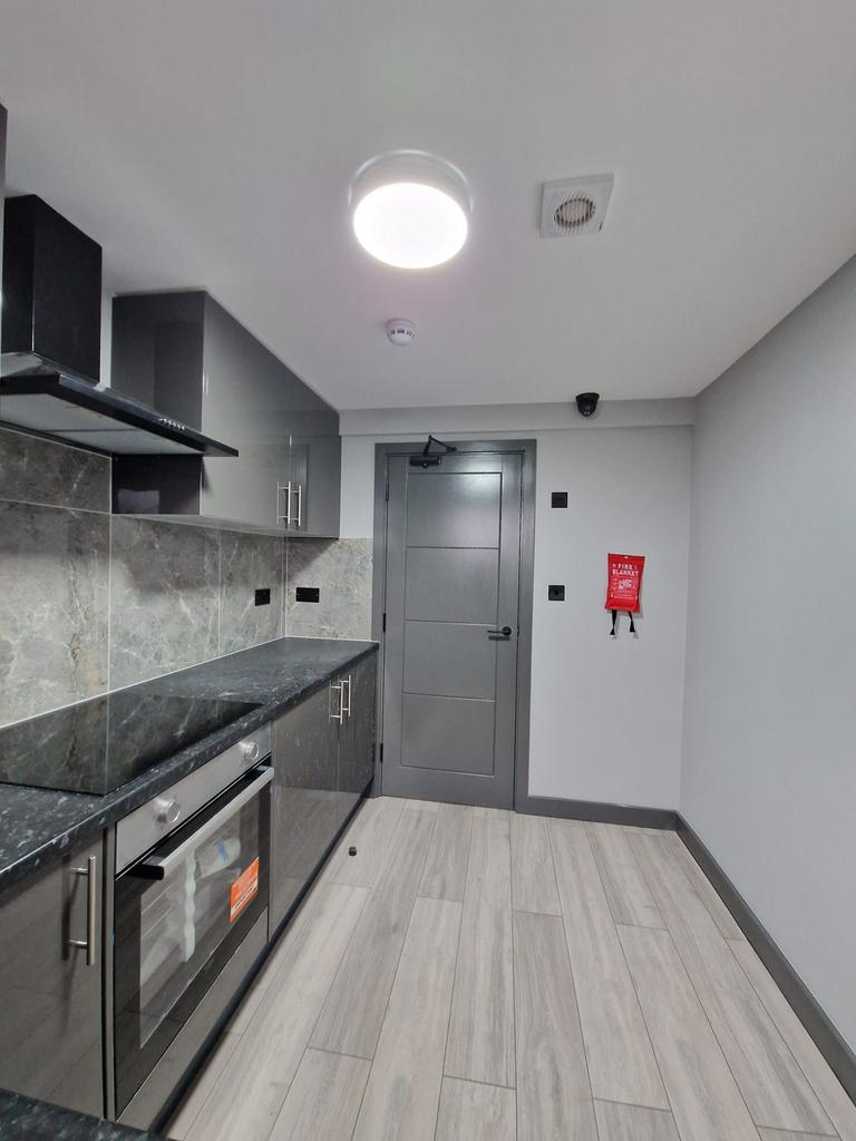 Modern galley-style kitchen with dark stone cou...