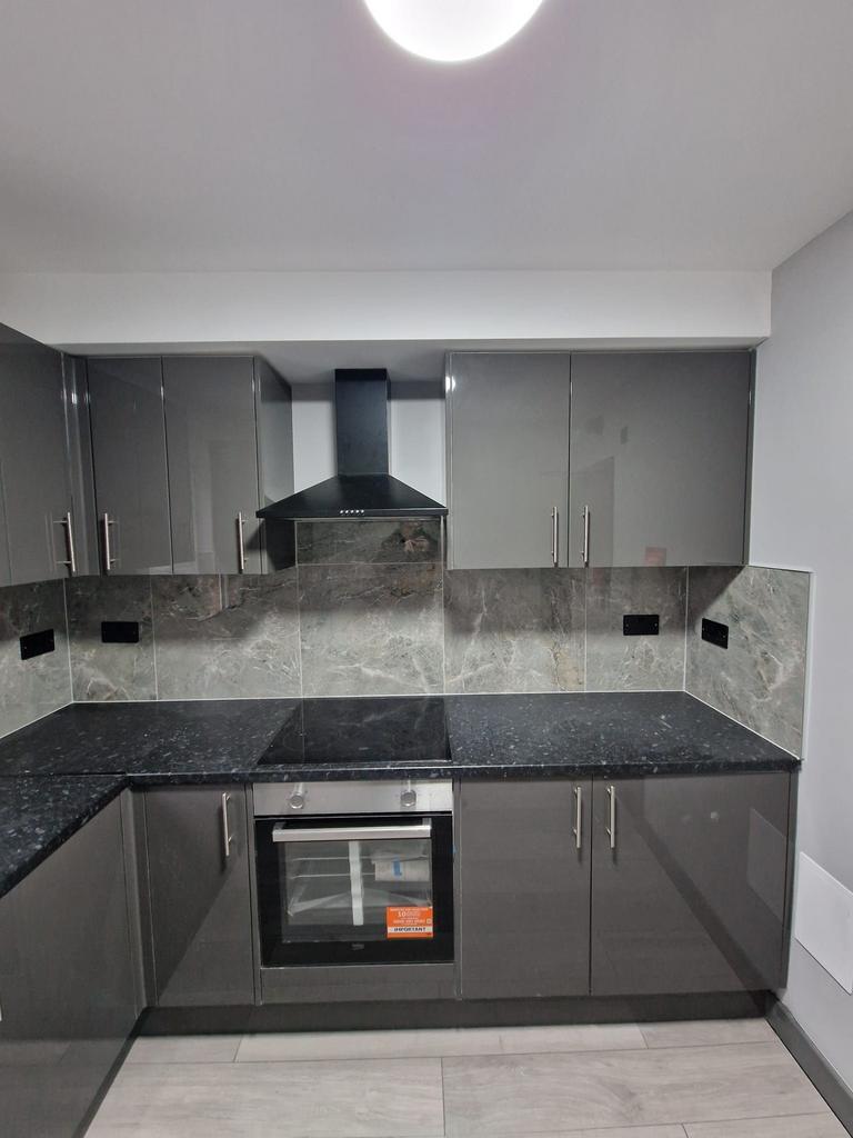 Modern fitted kitchen with glossy grey cabinets...