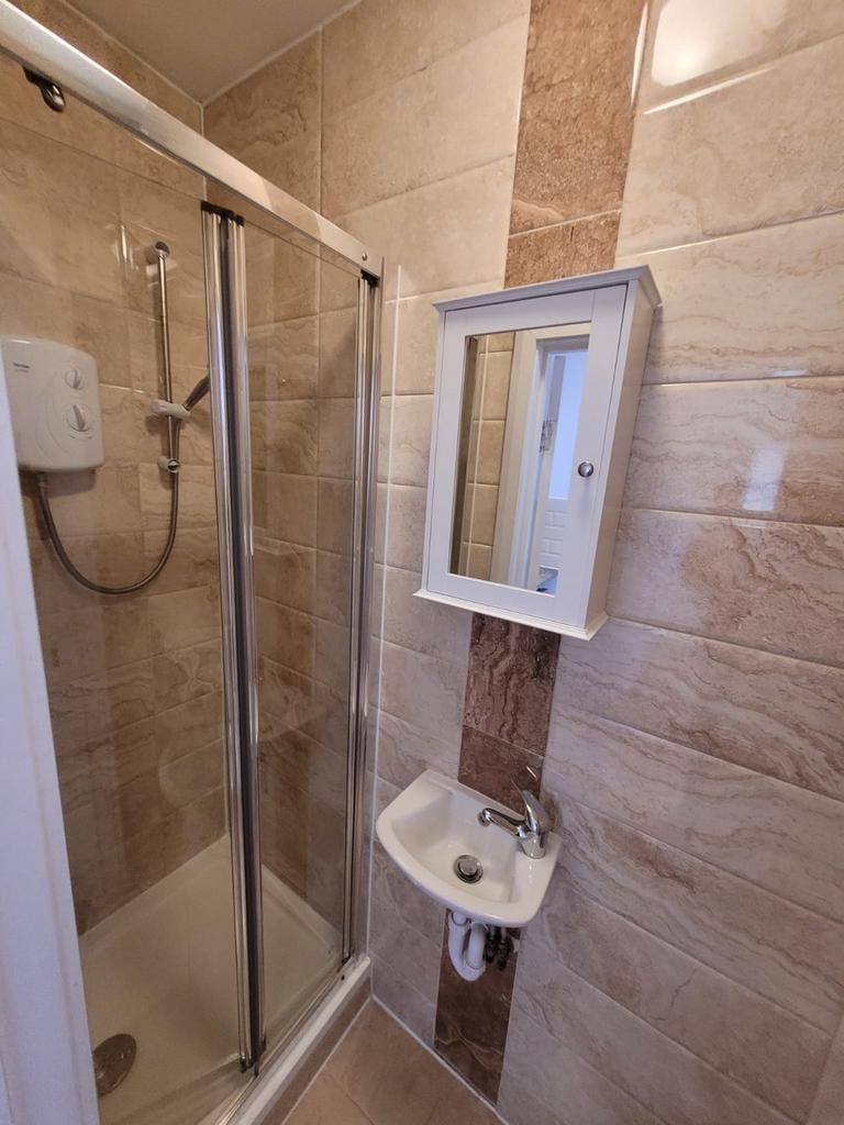 Compact modern bathroom with a corner shower en...