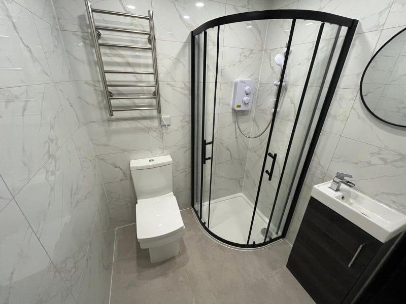 Modern tiled bathroom with a curved glass showe...