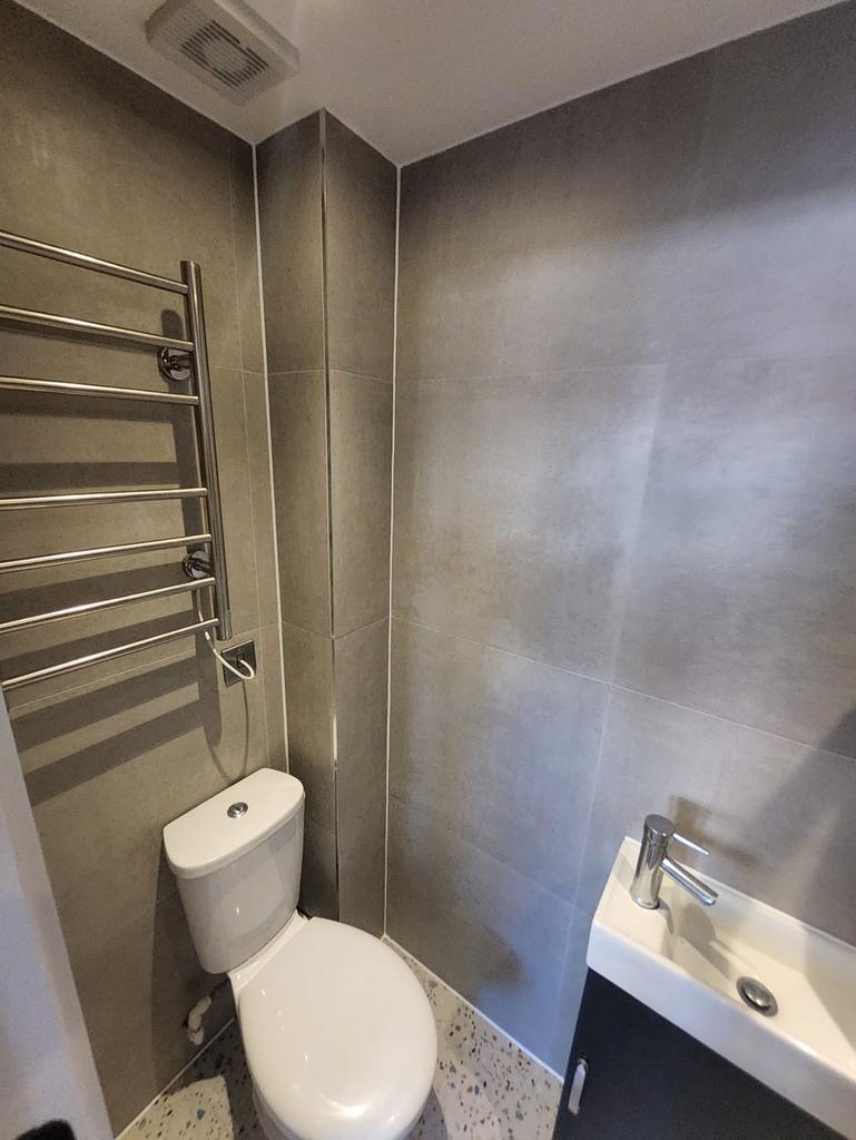 Compact, modern WC with tiled walls, chrome hea...