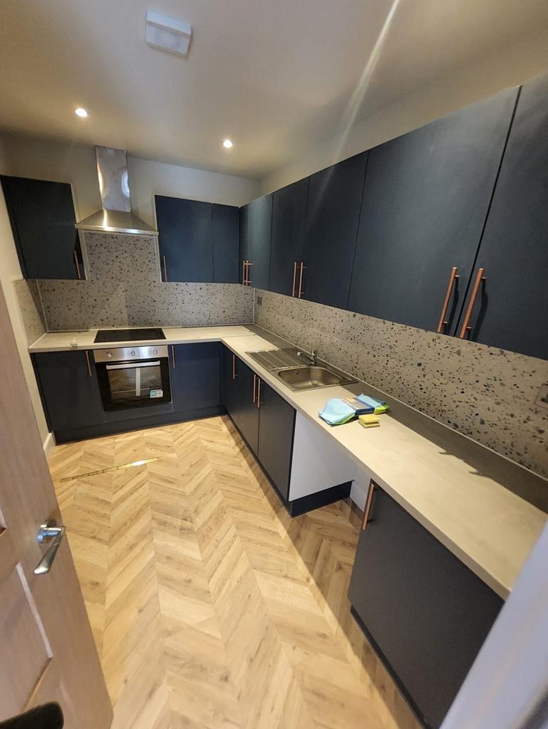 Modern galley kitchen with dark blue cabinets, ...
