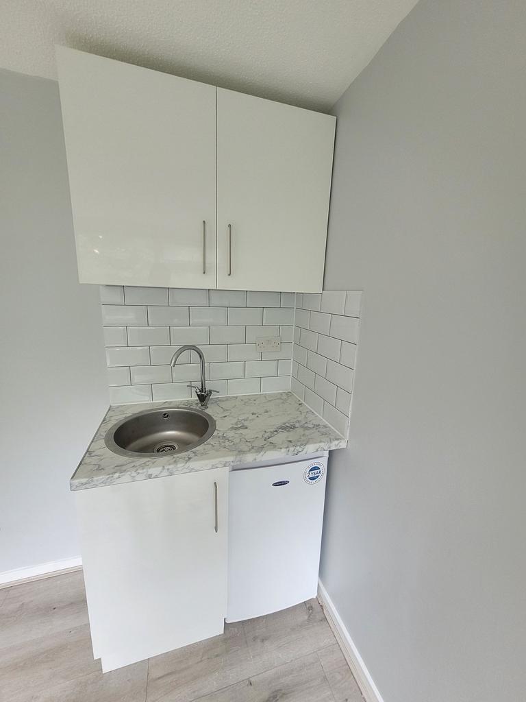 Compact modern kitchenette with glossy white ca...