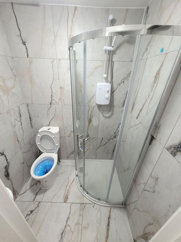 Bright, modern tiled bathroom with a curved gla...