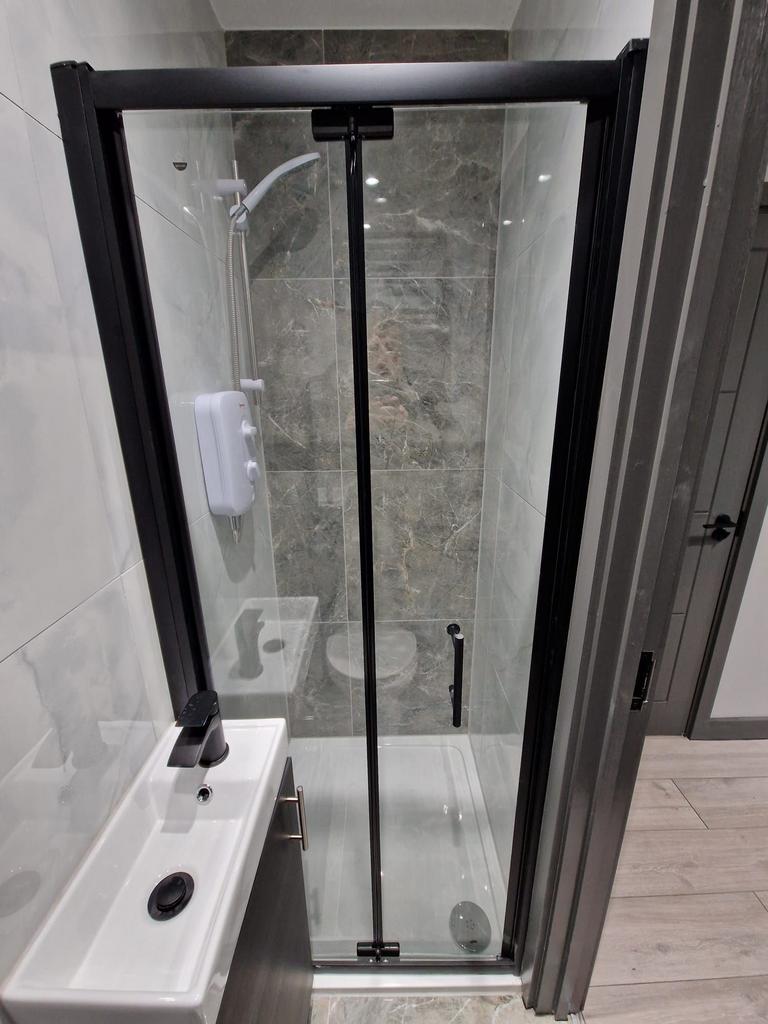 Compact modern bathroom with a glass-enclosed s...
