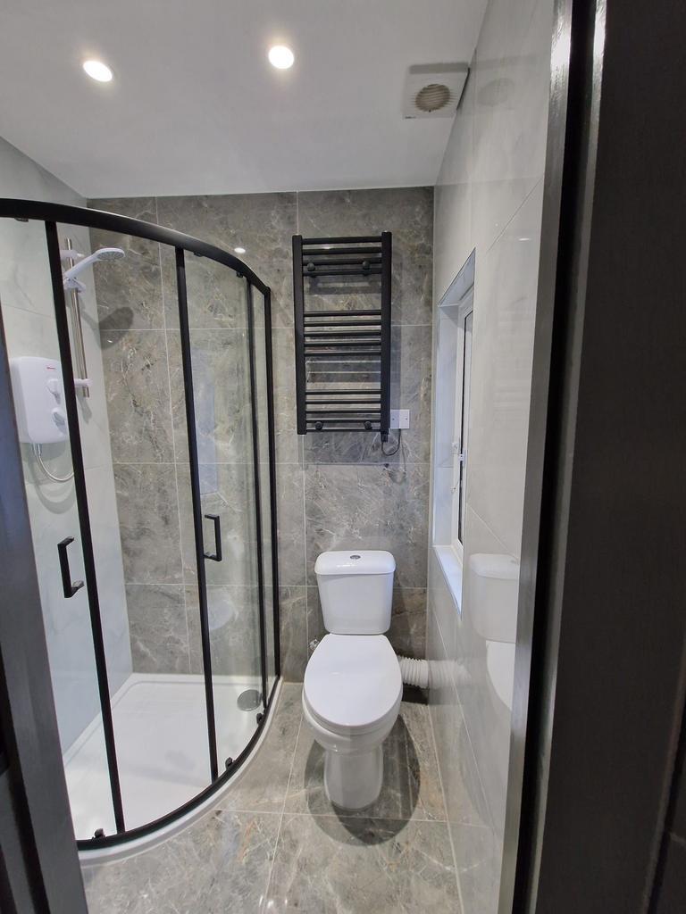 Modern tiled bathroom with a curved glass showe...
