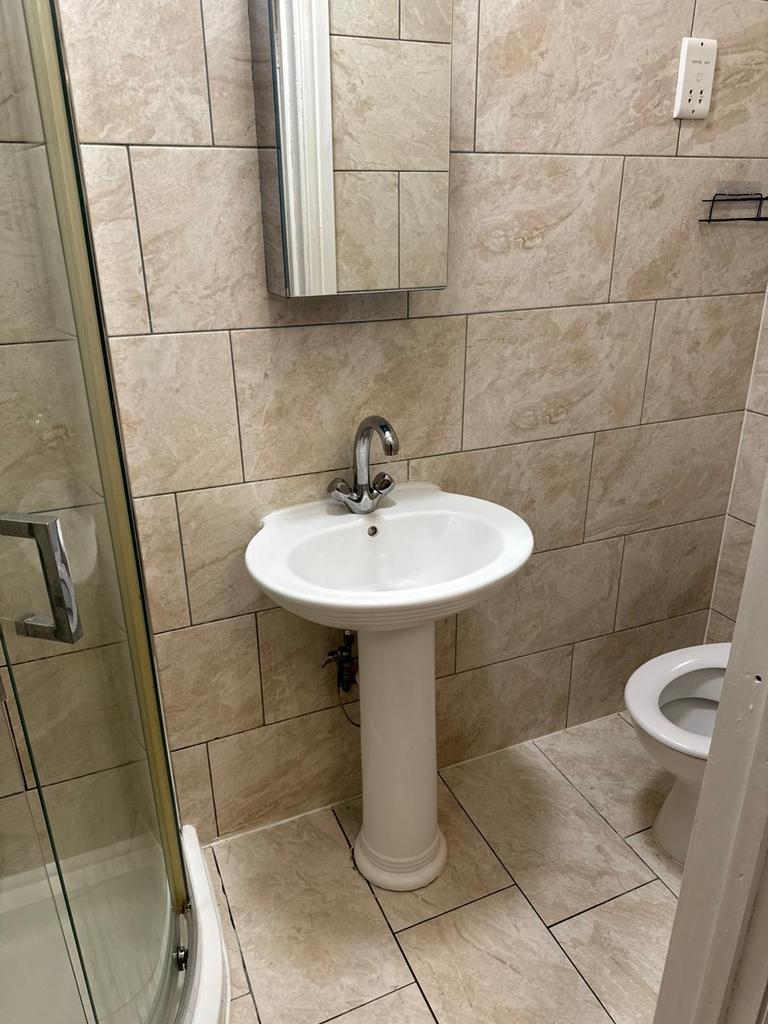 Bright tiled bathroom with a pedestal sink, mir...