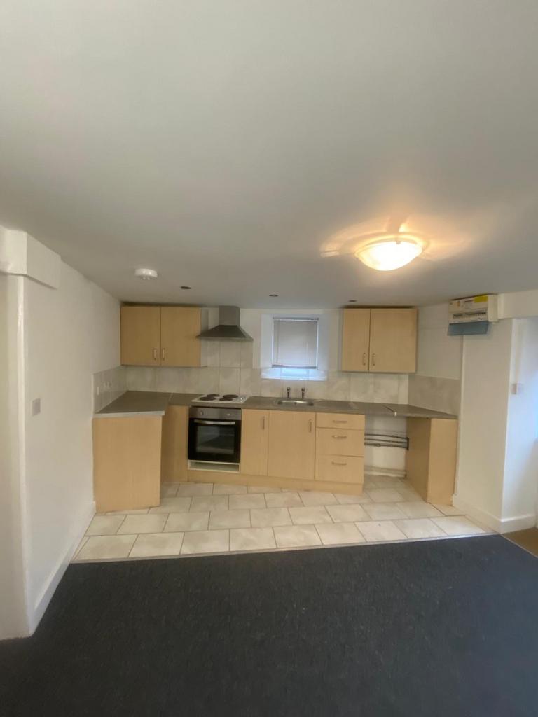 Well-kept open-plan kitchen with light wood cab...