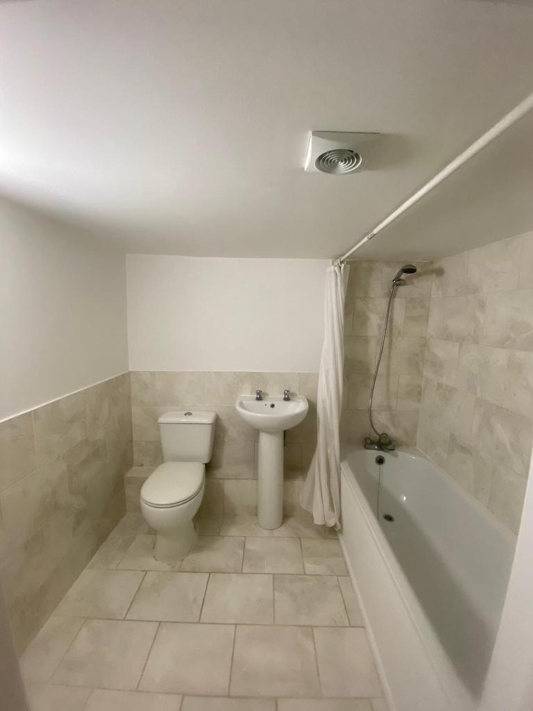 Bright, clean tiled bathroom with a full-size b...