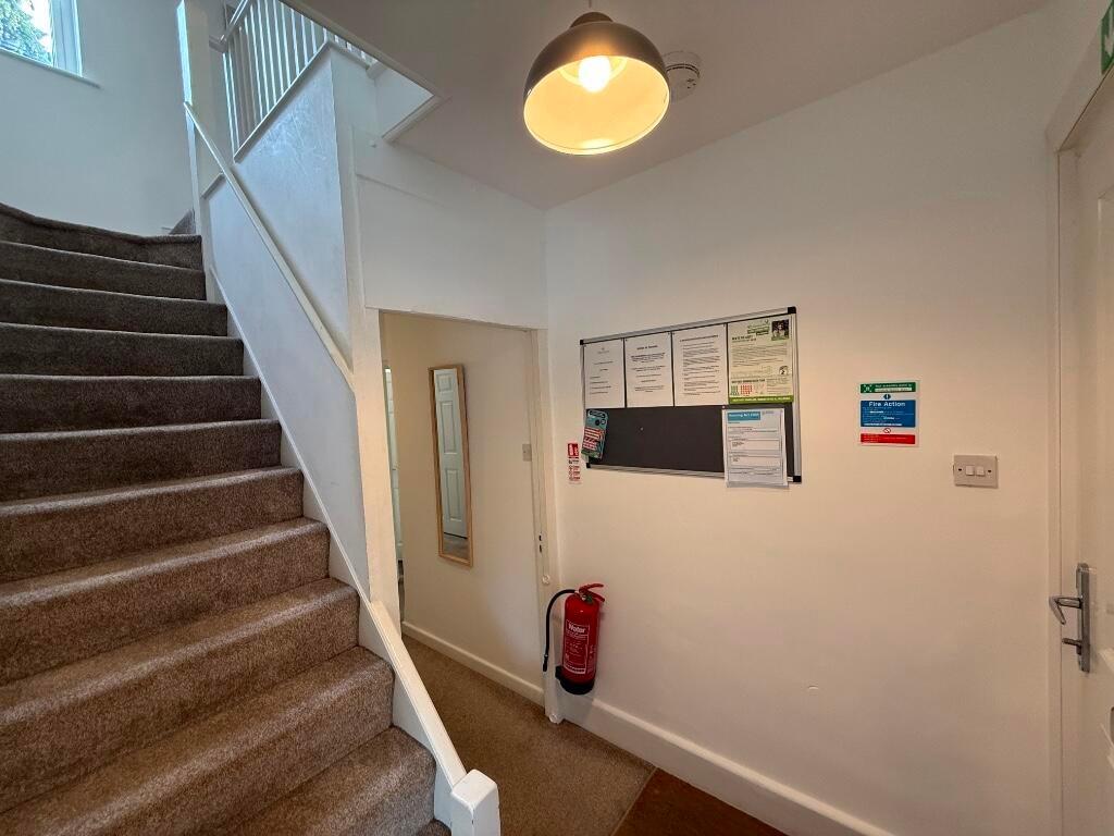 Bright, carpeted stairwell with noticeboard and...