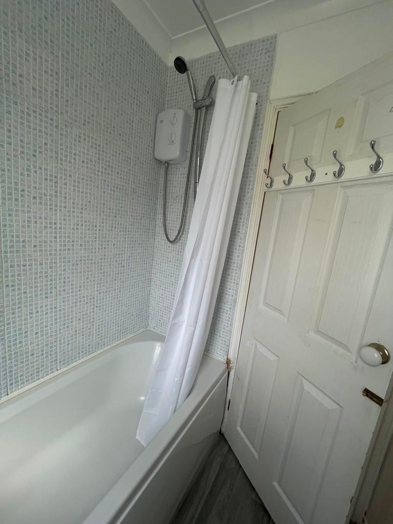 Bright compact bathroom with a white shower-ove...
