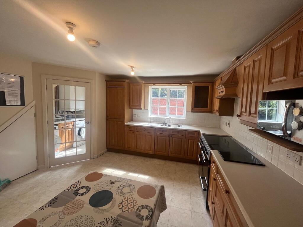 Bright fitted kitchen with wood cabinetry, larg...
